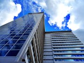 现代摩天大楼的低角度视图映照着蓝天和云彩，展现了城市建筑风貌