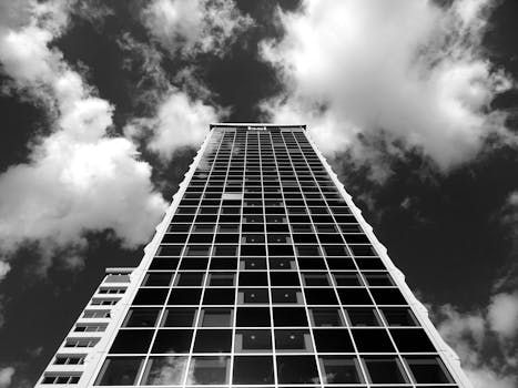 仰望多云天空中一座高大的现代摩天大楼