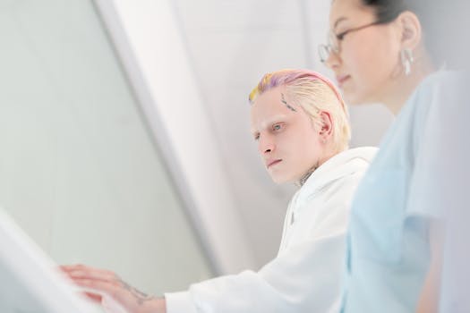 Two focused adults working together on a digital touch screen interface indoors.