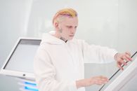 在现代场景中，一位纹身男子与一位彩色头发的人正在使用触摸屏亭
