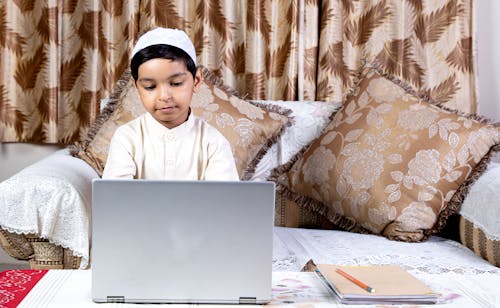 Free A Boy Using a Laptop while Sitting on a Couch Stock Photo