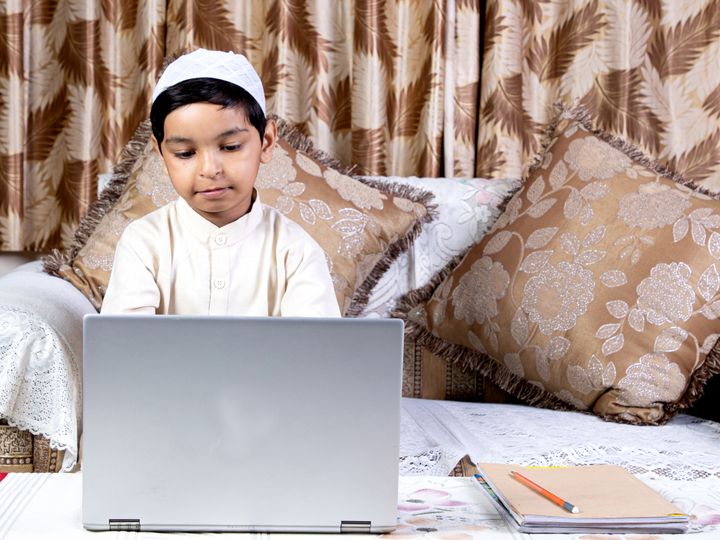 Boy learning Quran online at home on a laptop
