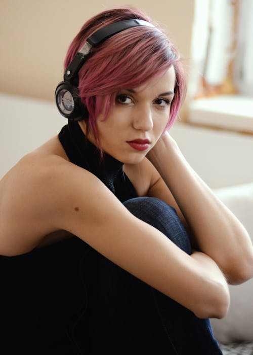 Young woman with colorful hair listening to music in headphones