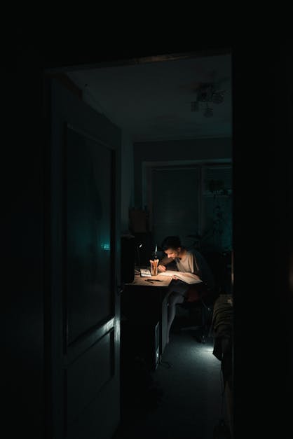 Student doing homework at table at night · Free Stock Photo