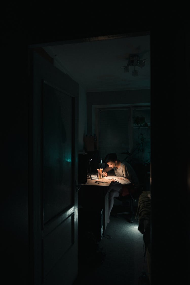 Student Doing Homework At Table At Night