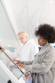 African American woman and Caucasian man using a touchscreen in a stylish setting.