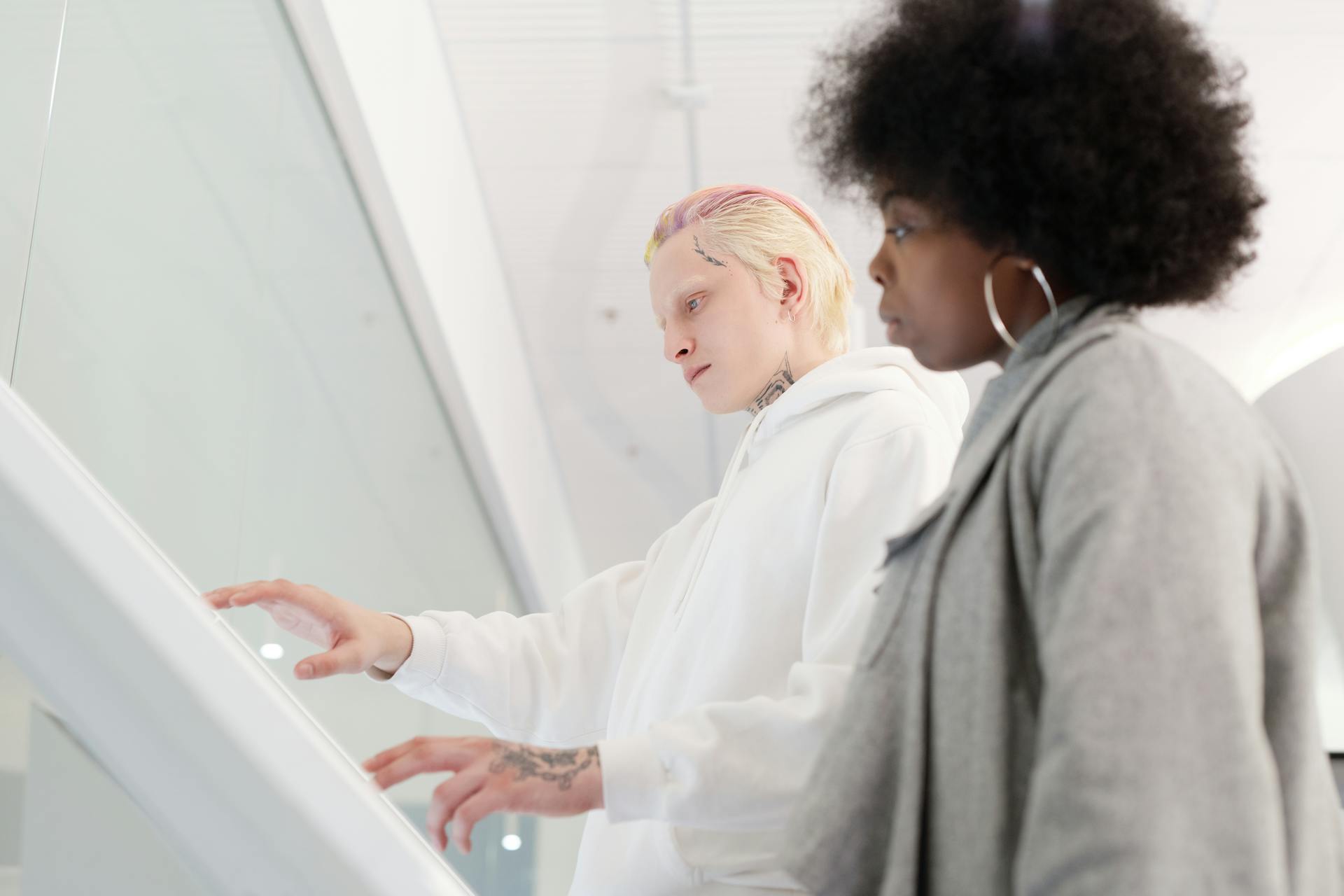 Two diverse individuals engaging with a touchscreen, showcasing modern technology use.