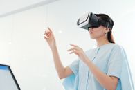 一名亚洲女性在室内专注地与虚拟现实耳机互动