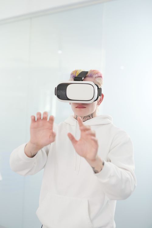 Free Tattooed person with colored hair immersed in virtual reality using a headset indoors. Stock Photo