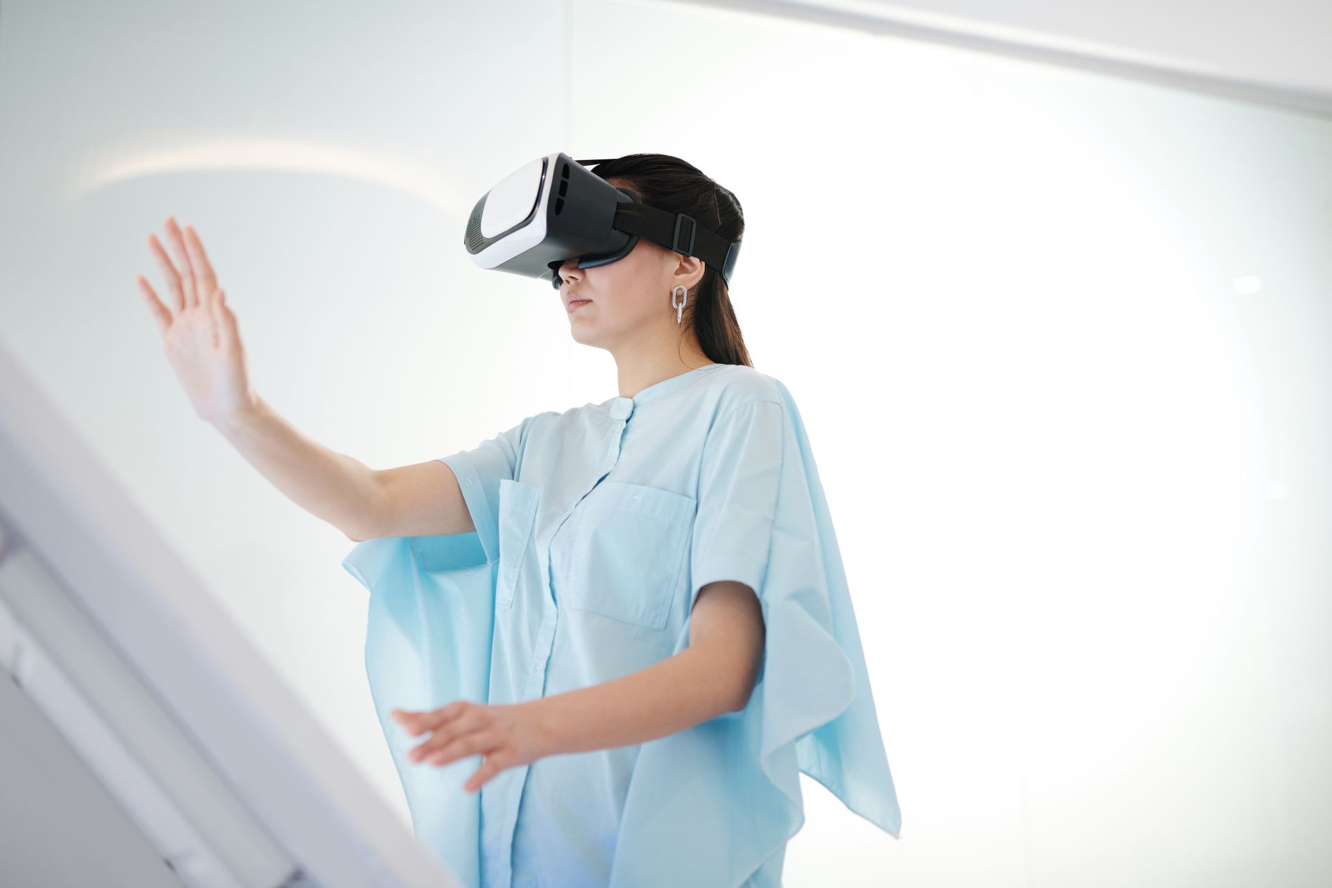 A woman wearing virtual reality goggles interacting with a digital interface inside a modern space.