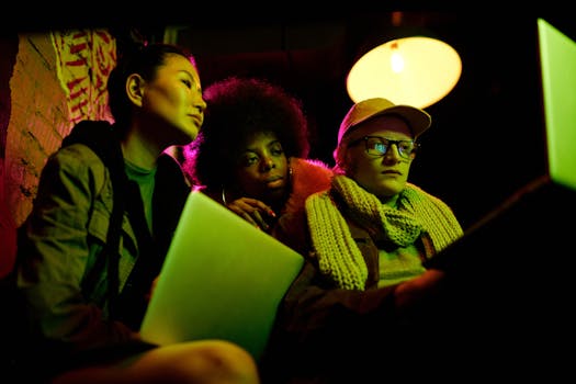 在充满活力的灯光下，多元化的三人组正专注地盯着笔记本电脑，这突显了网络安全主题