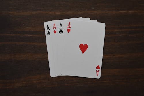 Top view of combination of four aces of different suits in poker on wooden table