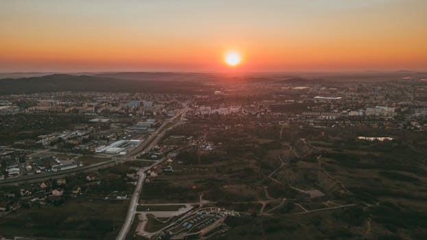 A breathtaking aerial view of a cityscape with the sun setting on the horizon, capturing urban beauty.