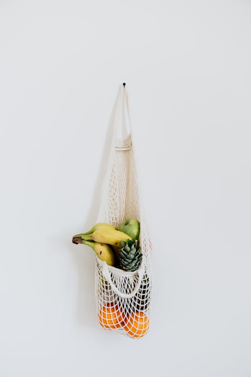 Fruits in Net Mesh Bag Hanging on the White Wall