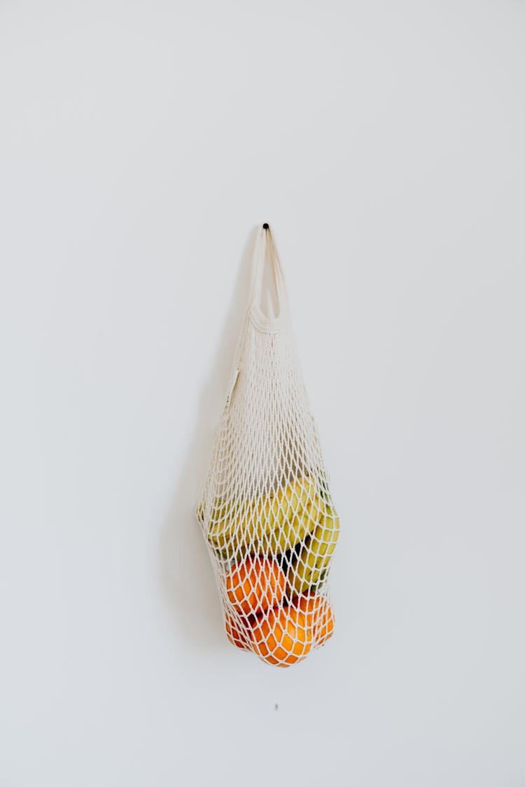 Bag Of Fruit Hanging On White Wall