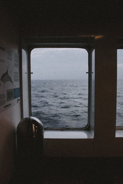 Interior or dark room on passenger ship with brochure on wall and window