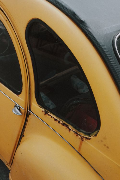 Free Window with round corners and small metallic handle on door on side part of old shabby yellow retro automobile Stock Photo