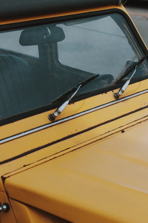 Metallic wipers on rectangular dirty windscreen of old shabby retro car in daylight