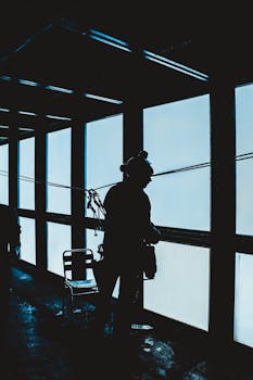 Silhouetted worker with safety gear inside a high-rise building, highlighting industrial heights.