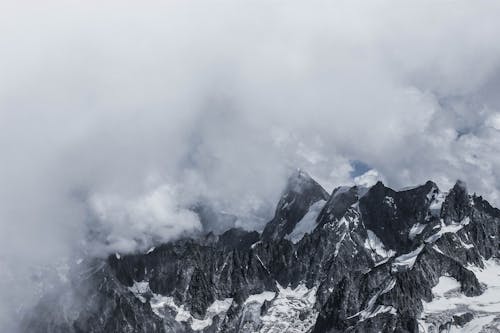 Majestic ridge with rocky peaks covered with snow and hidden with cloudy sky