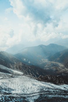 A stunning view of snow-covered mountains and valleys under dramatic clouds.