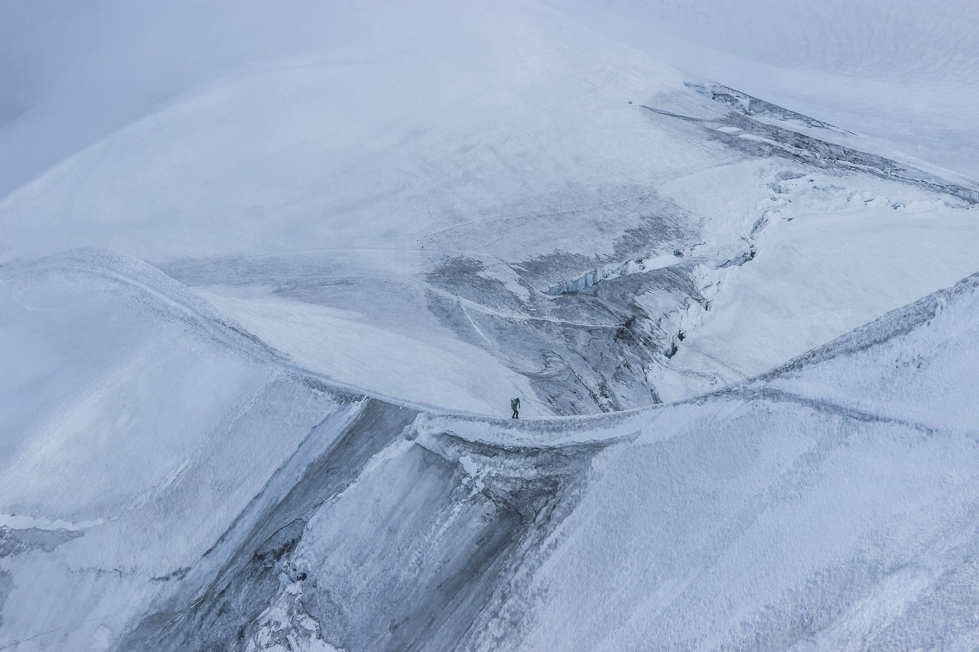 A lone climber bravely navigates a dramatic icy mountain ridge, exhibiting the spirit of adventure.
