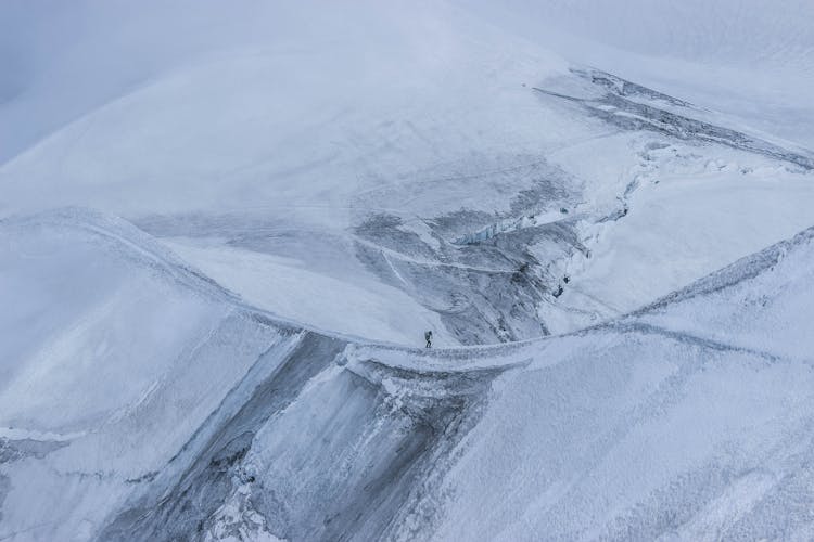 Distant Alpinist Climbing On Mountain Ridge