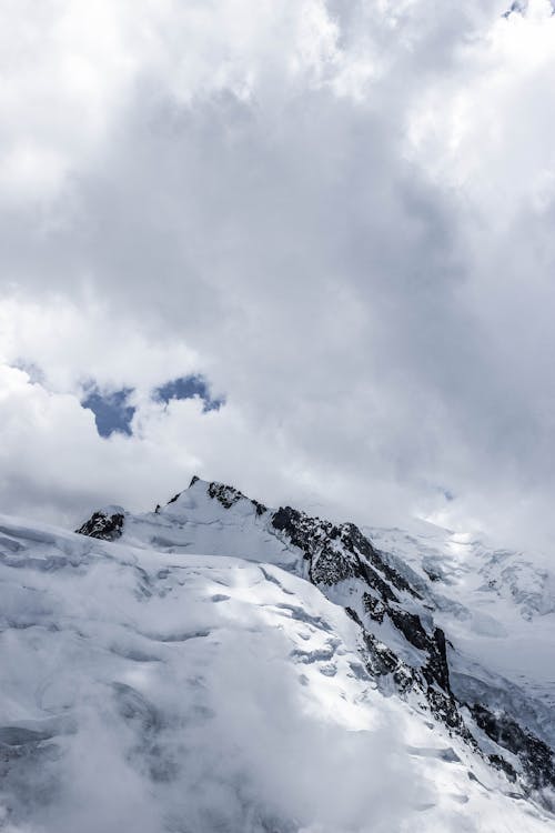 Rocky mountains with sharp peaks covered with snow and ice against majestic cloudy sky