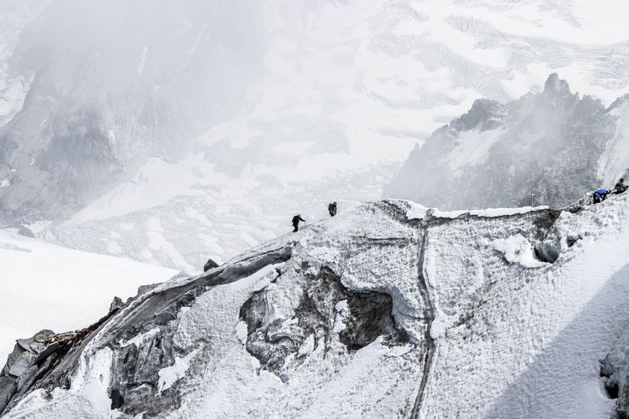Distant alpinists climbing a snowy mountain slope