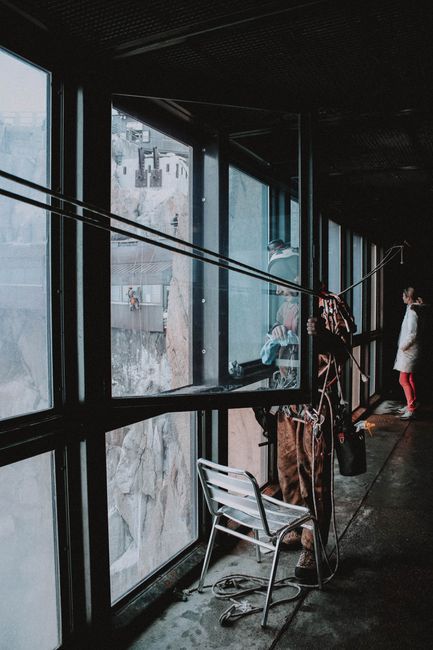 Faceless professional industrial tower climber with alpinist equipment standing near opened window on building upper storey