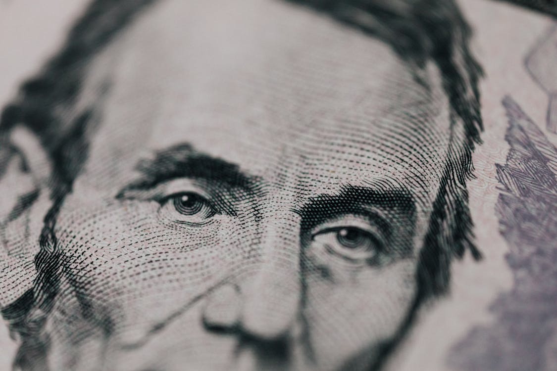 Closeup of male American president printed on five dollar bill and looking away pensively