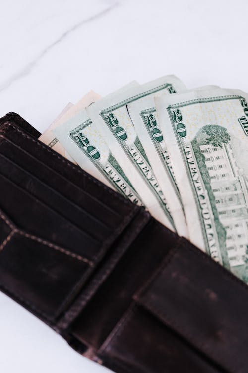 Free From above of black leather wallet with cash money of twenty dollars placed on white table Stock Photo