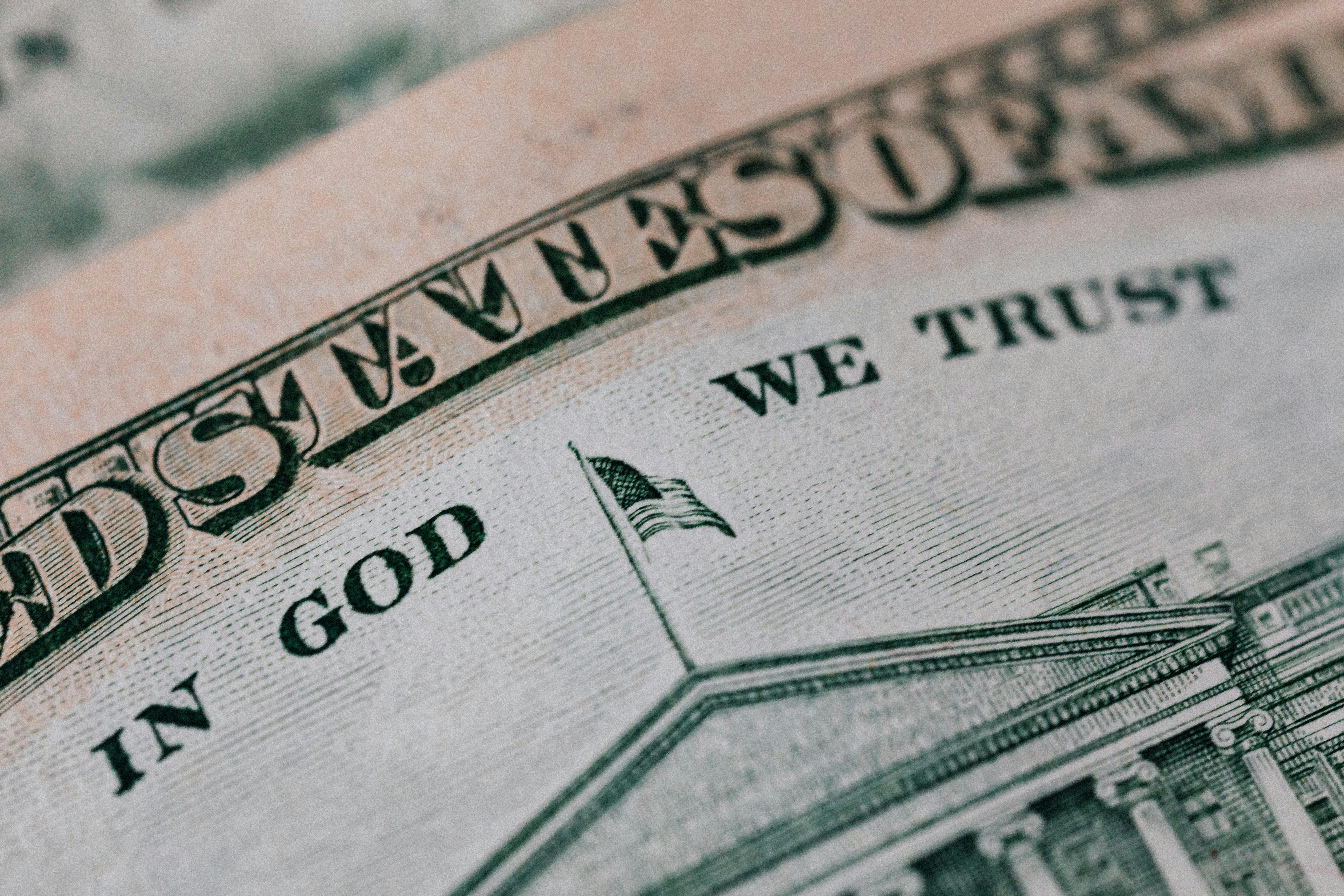 Closeup of ten dollar with inscription In God We Trust bill placed on table with different money