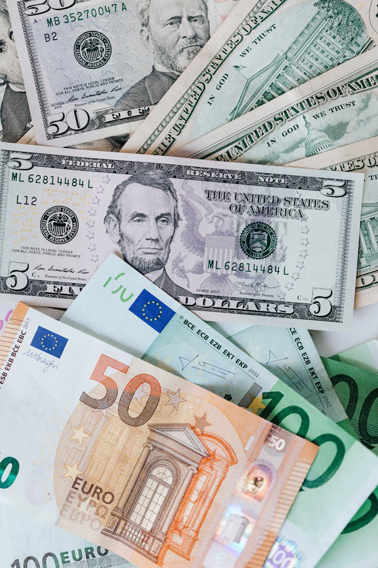 Stack Of Different Currency With Photo Of Men And Buildings