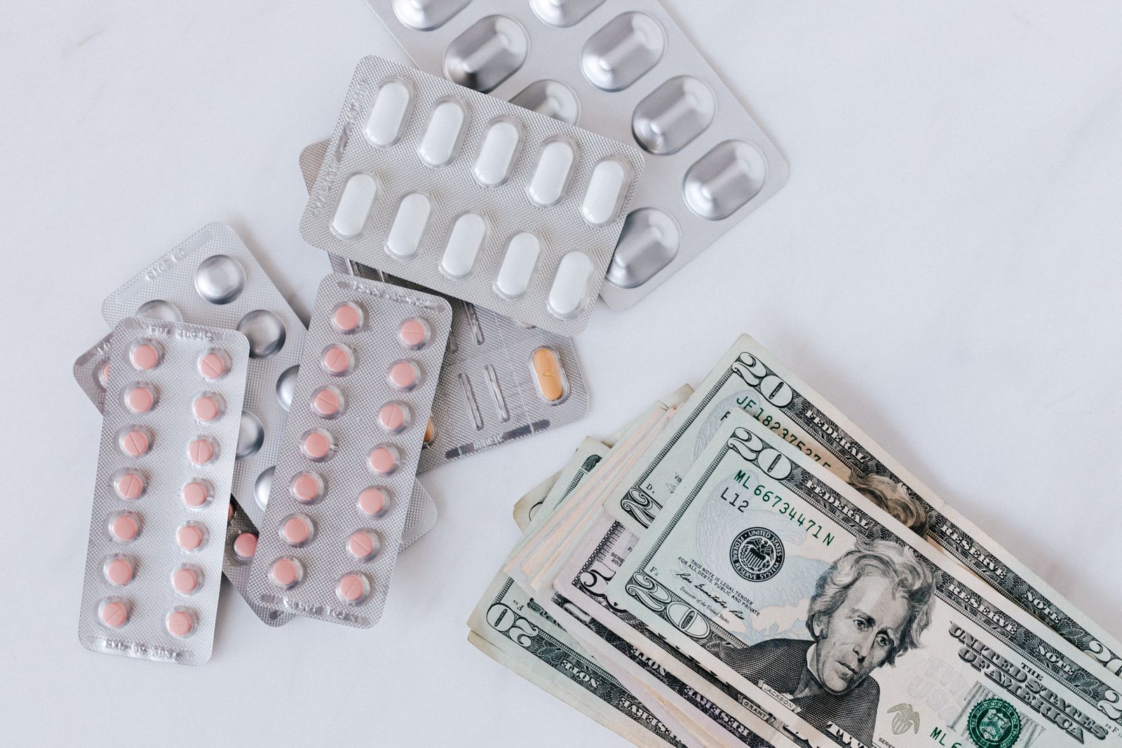 Medication blister packs beside US dollar bills. Without insurance, the cost of GLP-1 drugs like Ozempic is a real barrier worth planning around.
