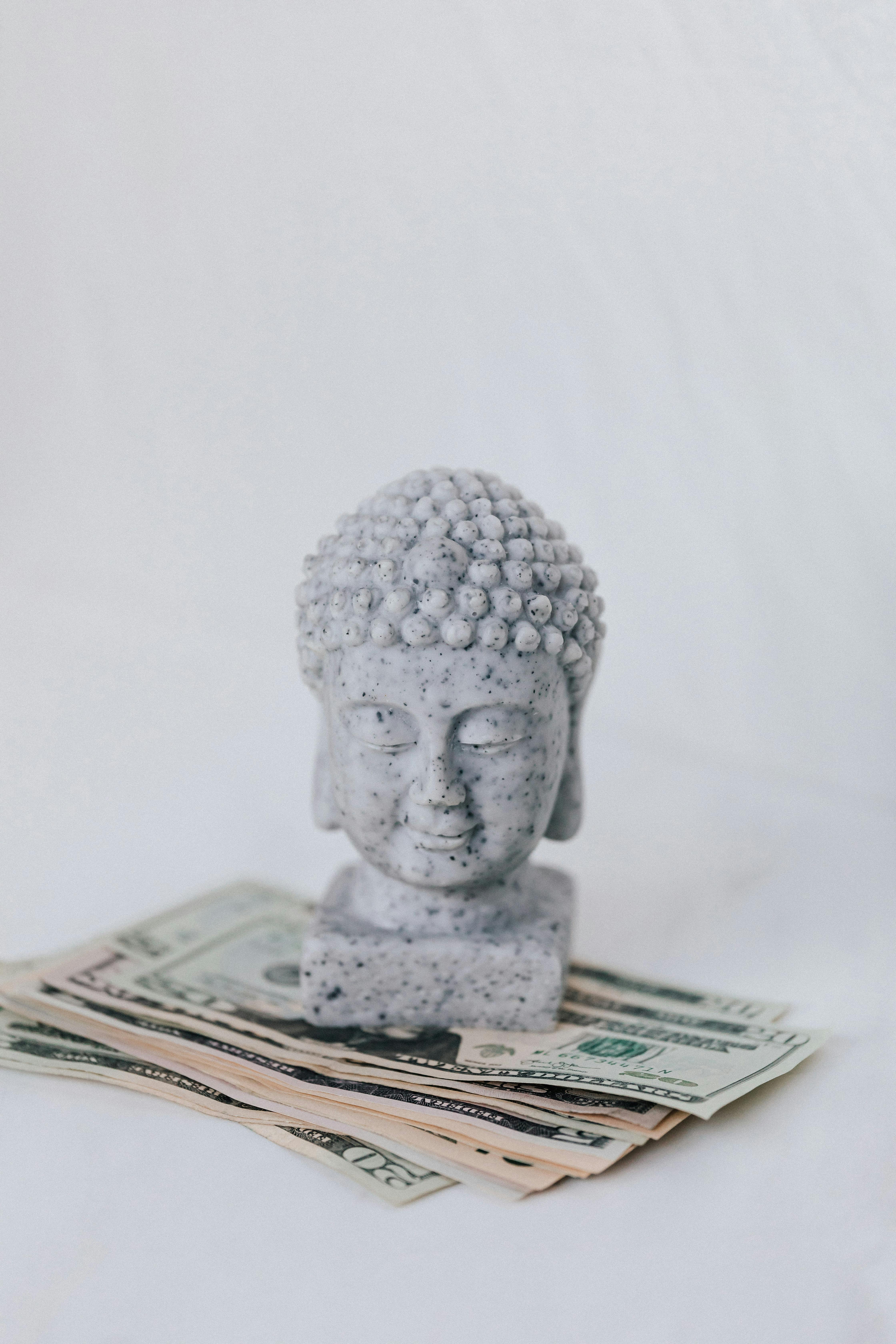 tibetan sculpture on heap of american dollars on white background