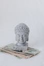 Tibetan sculpture on heap of American dollars on white background