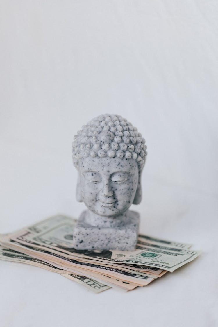 Tibetan Sculpture On Heap Of American Dollars On White Background