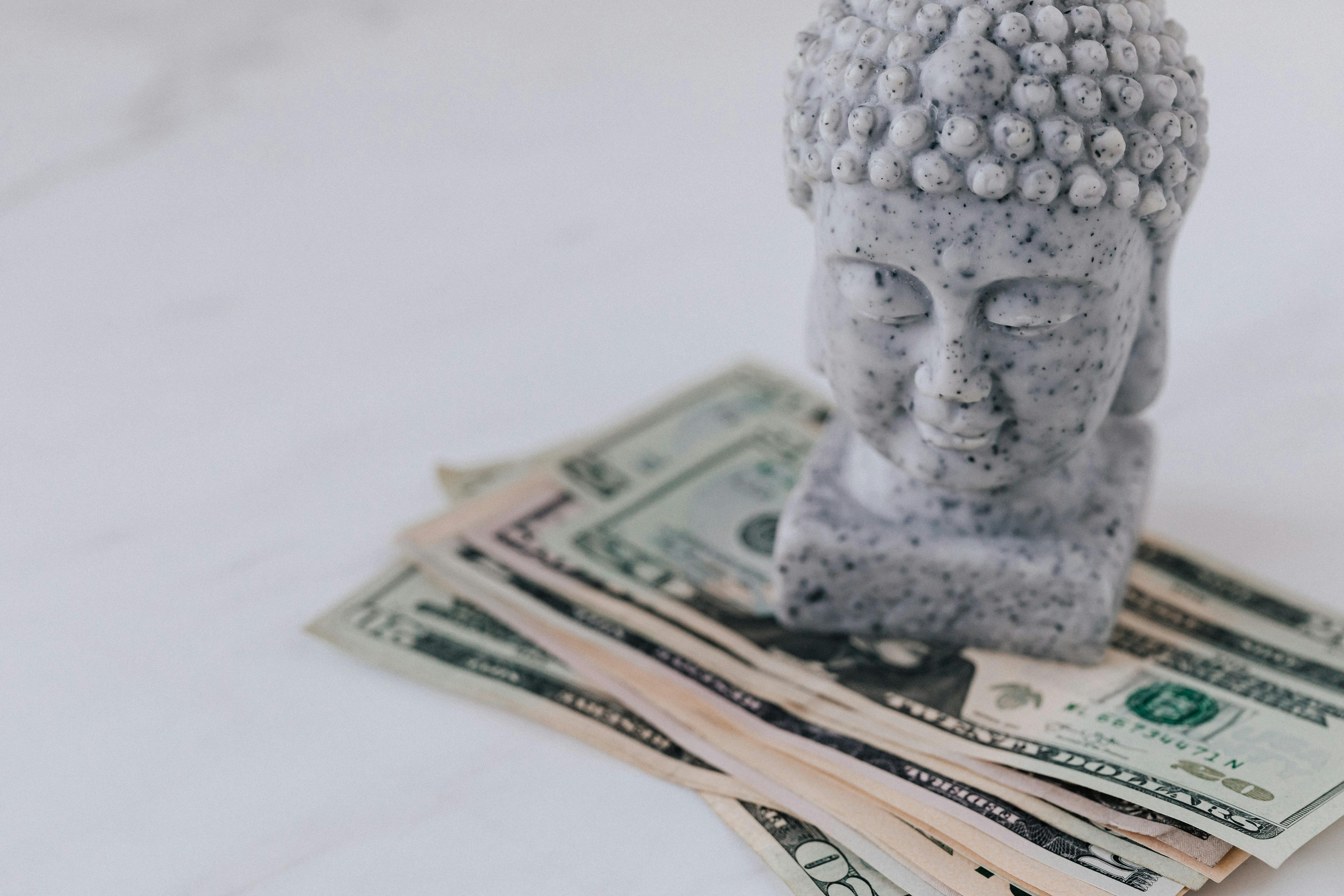 bust of buddha on pile of paper money