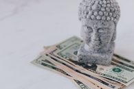 白色台面上堆放着大理石装饰的佛半身像和美元