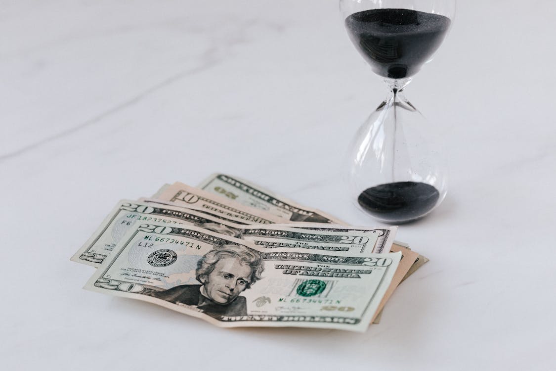 Free Hourglass near Heap of American Dollars Stock Photo