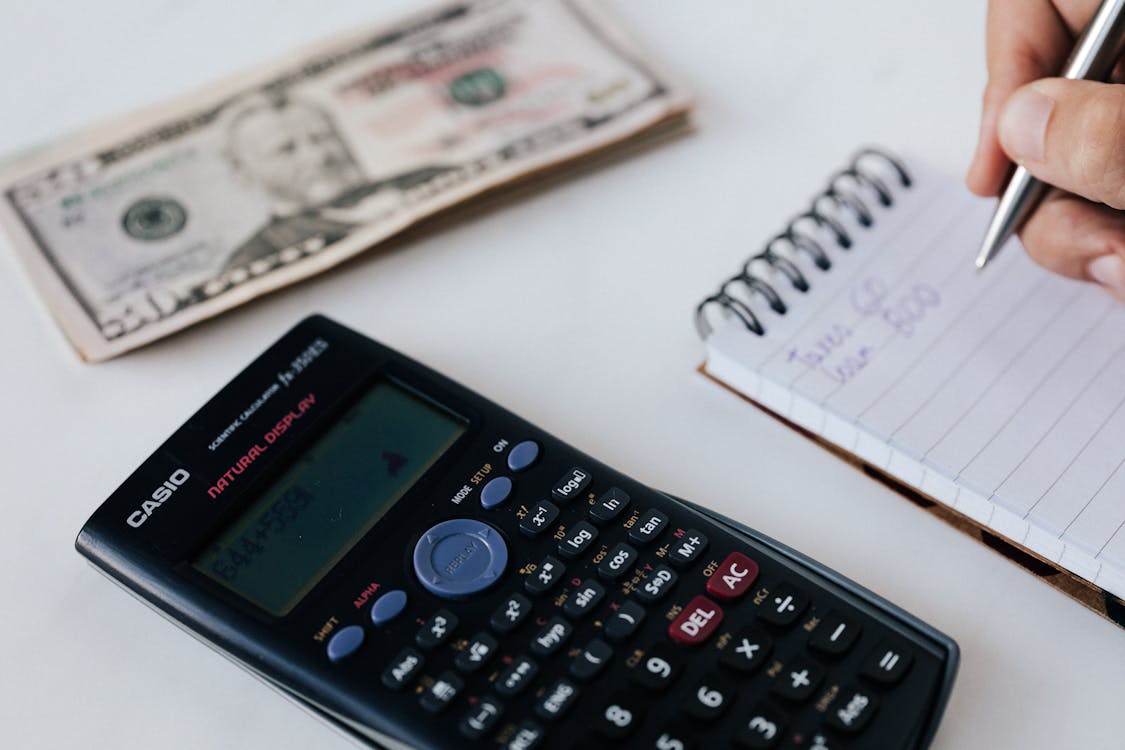 Free Crop unrecognizable accountant counting savings using notebook and calculator Stock Photo