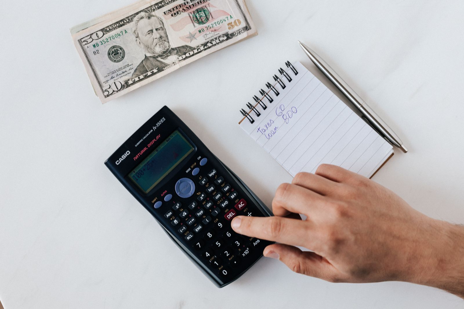 Calculatrice, billets et carnet de notes symbolisant un calcul financier