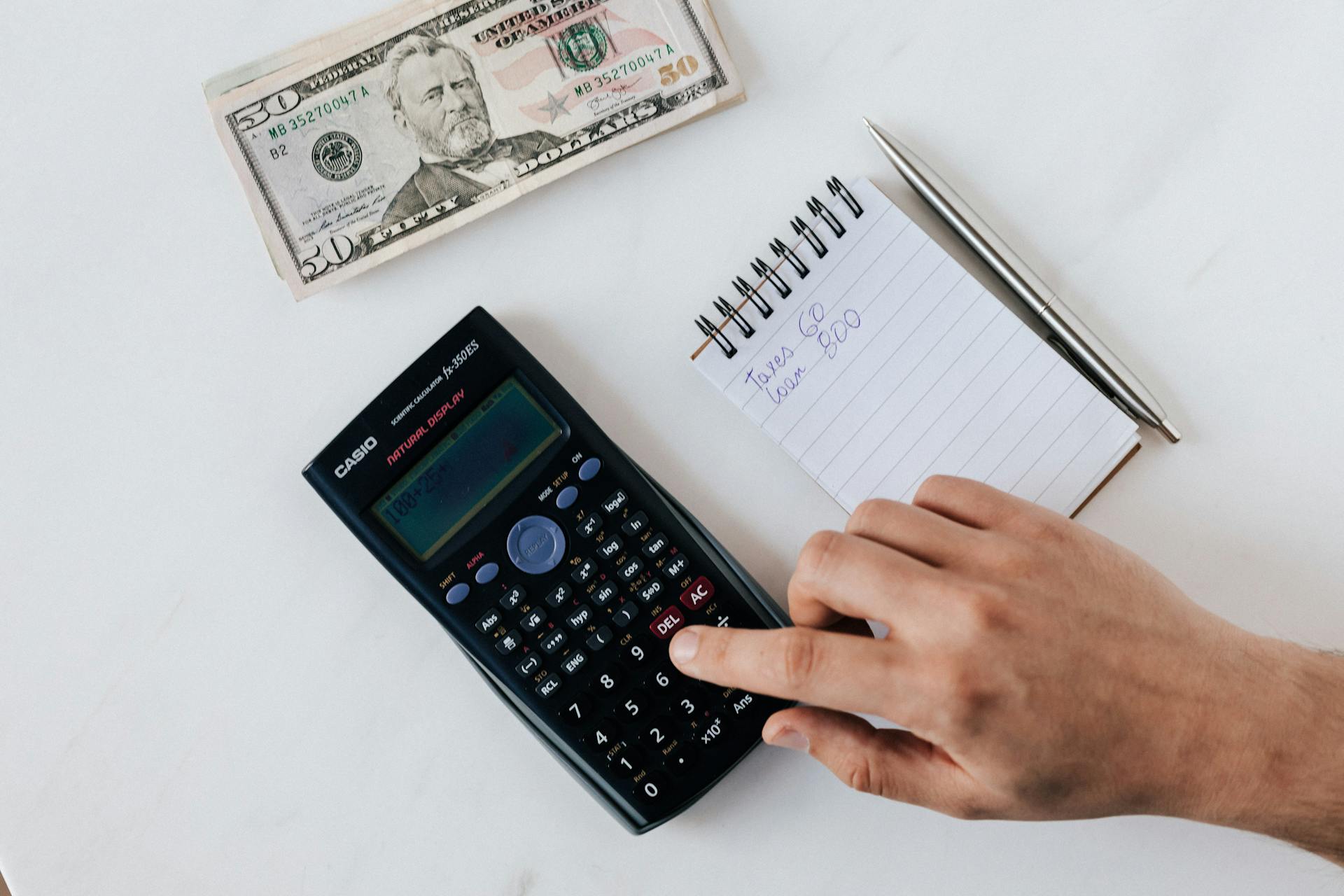 Crop faceless accountant using calculator while making budget