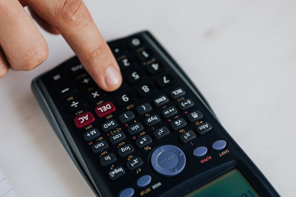 Free From above of crop anonymous economist calculating on calculator with plastic buttons while making budget on marble table Stock Photo