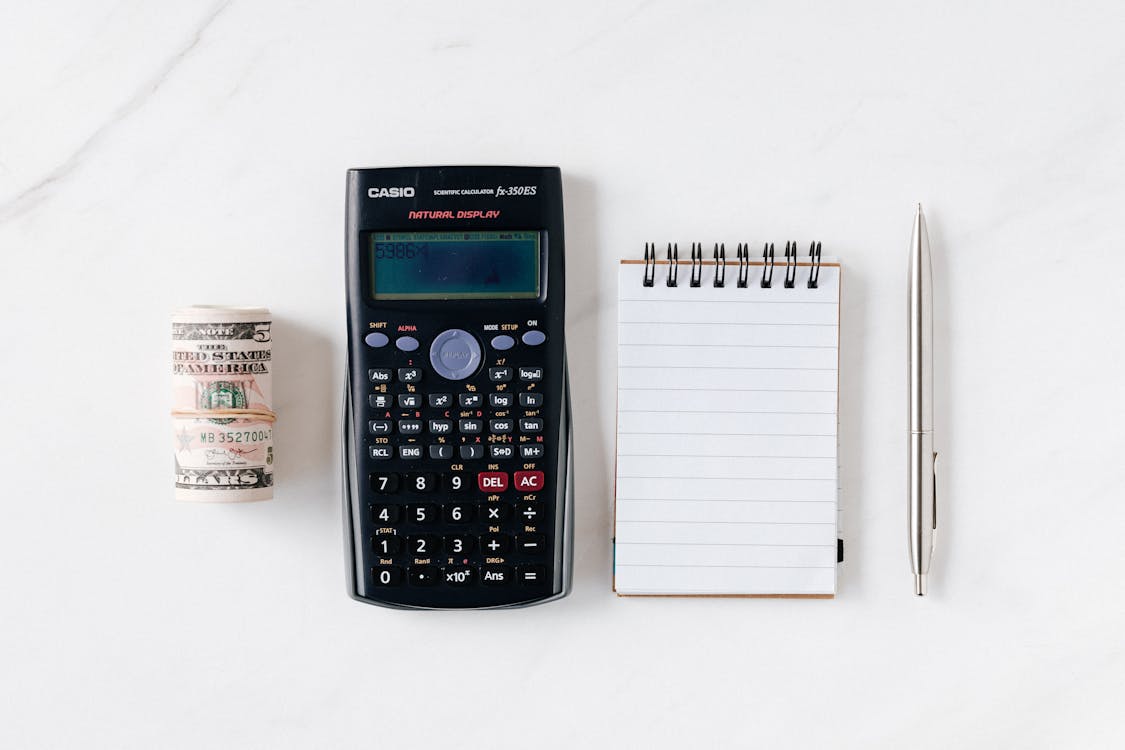  Composition of calculator with paper money and notebook with pen 