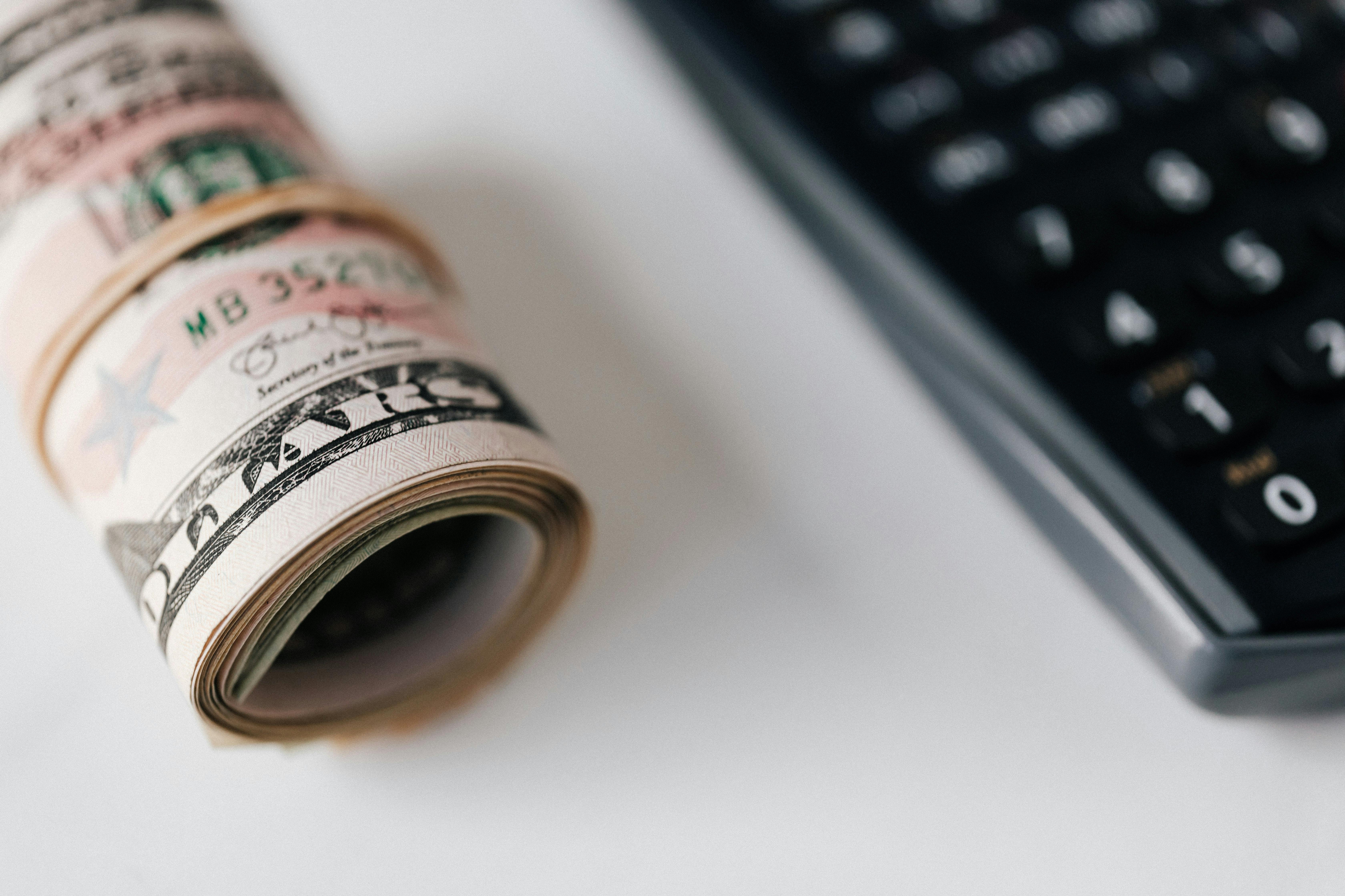 roll of dollar banknotes near calculator on table