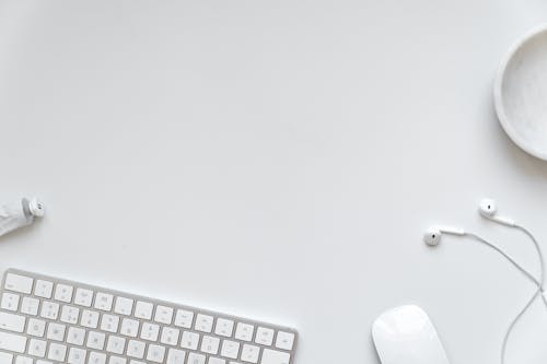 White Desk with Keyboard and Earbuds