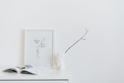 Free A serene minimalist desk setup featuring art, book, and glass on a white surface. Stock Photo