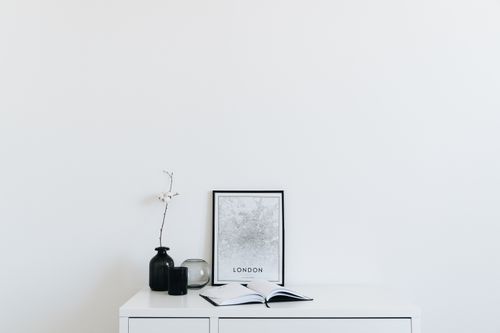 Free A minimalist interior with white decor featuring a book, vase, and a framed map. Stock Photo